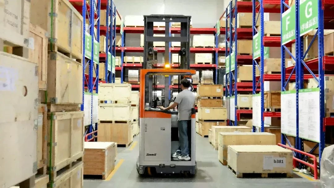 Operator driving man-up VNA forklift inside finished goods warehouse cross aisle1 Operator driving man-up VNA forklift inside finished goods warehouse cross aisle1