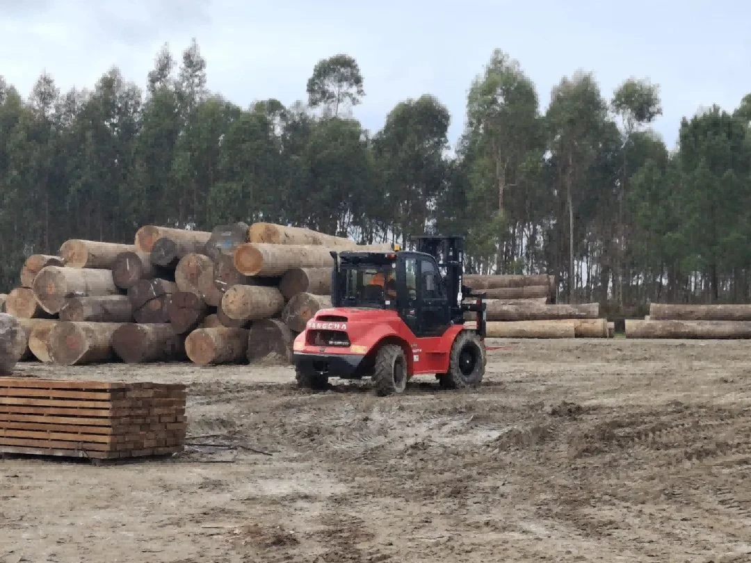 Rough terrain forklift transporting timber on muddy forest yard1 Rough terrain forklift transporting timber on muddy forest yard1
