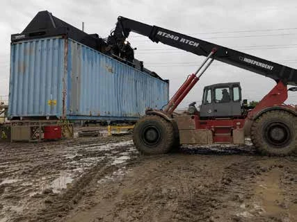 Heavy rough terrain container handler operating on wet muddy ground Heavy rough terrain container handler operating on wet muddy ground