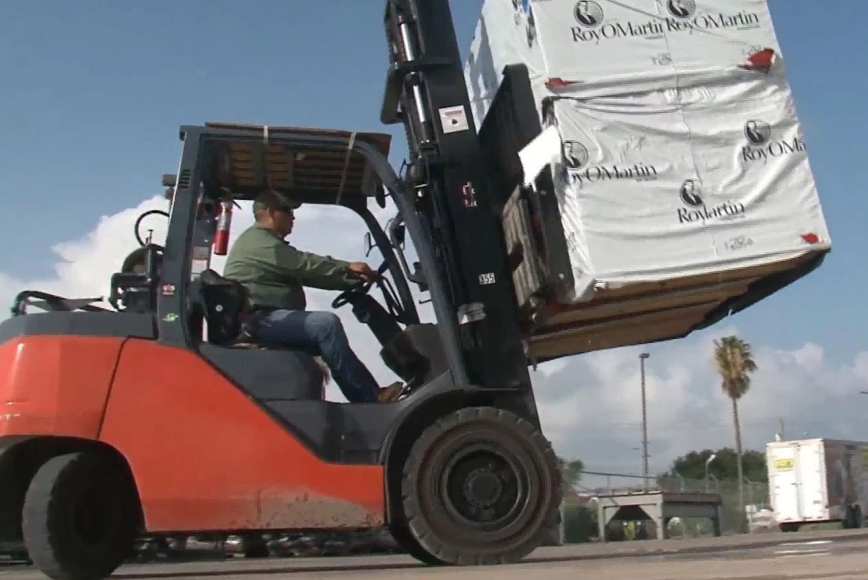 Pneumatic tyre forklift moving wrapped cargo over rough outdoor ground1 Pneumatic tyre forklift moving wrapped cargo over rough outdoor ground1